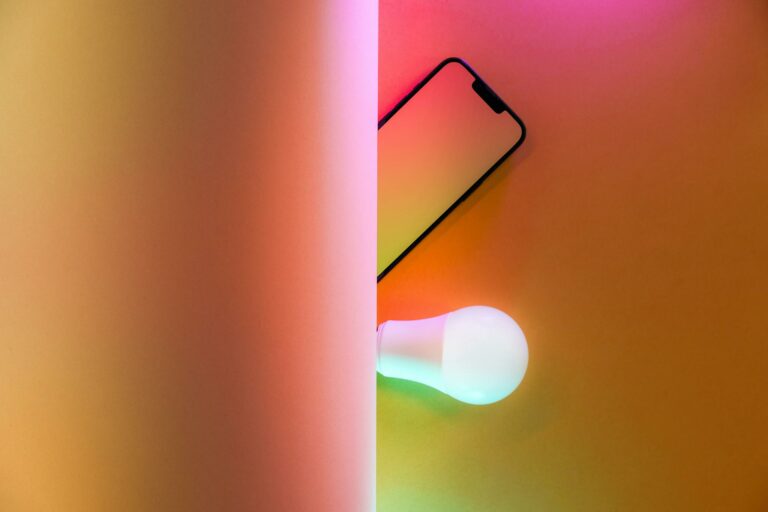 Creative abstract image featuring a smart light bulb and smartphone with colorful illumination.